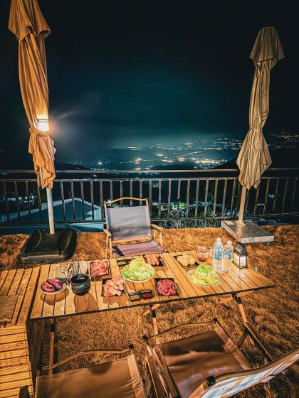 Bàn BBQ đêm trên sân cỏ nhìn xuống đèn thung lũng